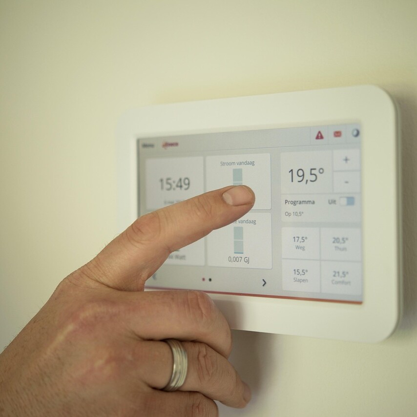 Personne réglant un thermostat numérique pour contrôler la température intérieure