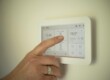Personne réglant un thermostat numérique pour contrôler la température intérieure