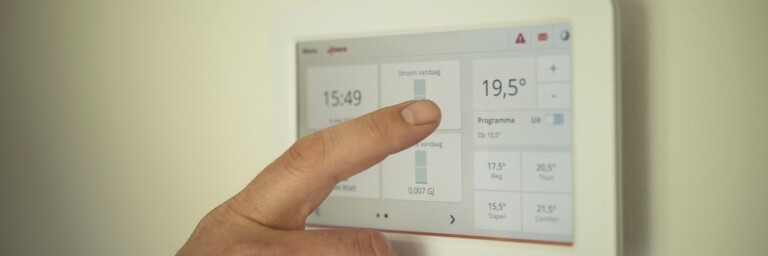 Personne réglant un thermostat numérique pour contrôler la température intérieure