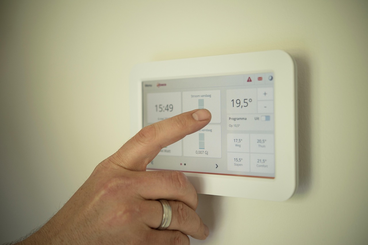 Personne réglant un thermostat numérique pour contrôler la température intérieure